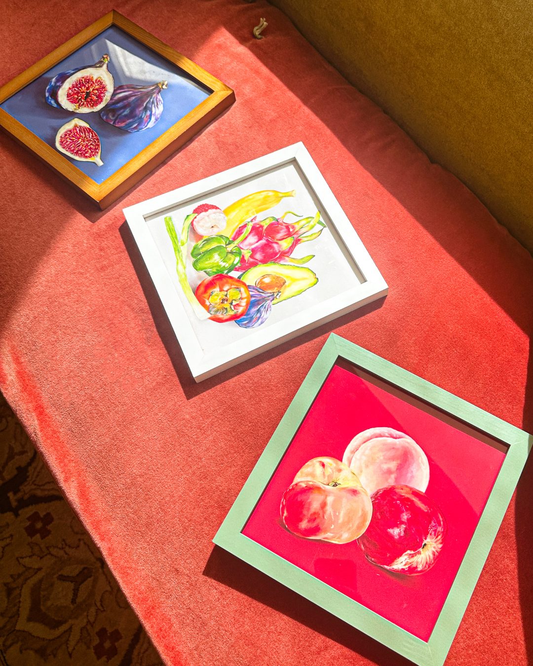 Three framed Fruit Stand paintings in warm light: figs, mixed produce and peaches