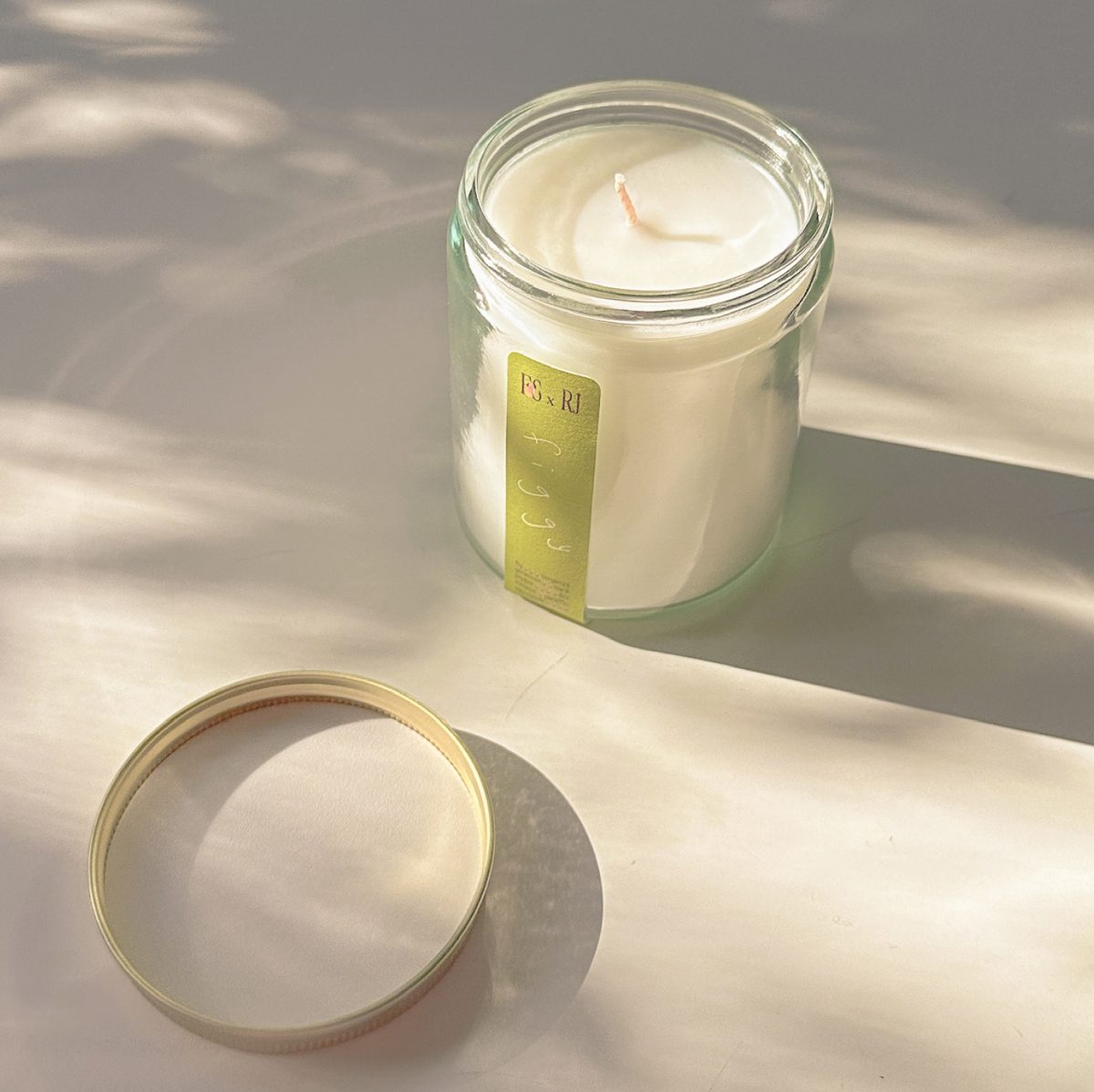 Fruit Stand candle in a glass jar with a green fig label, in dappled sunlight