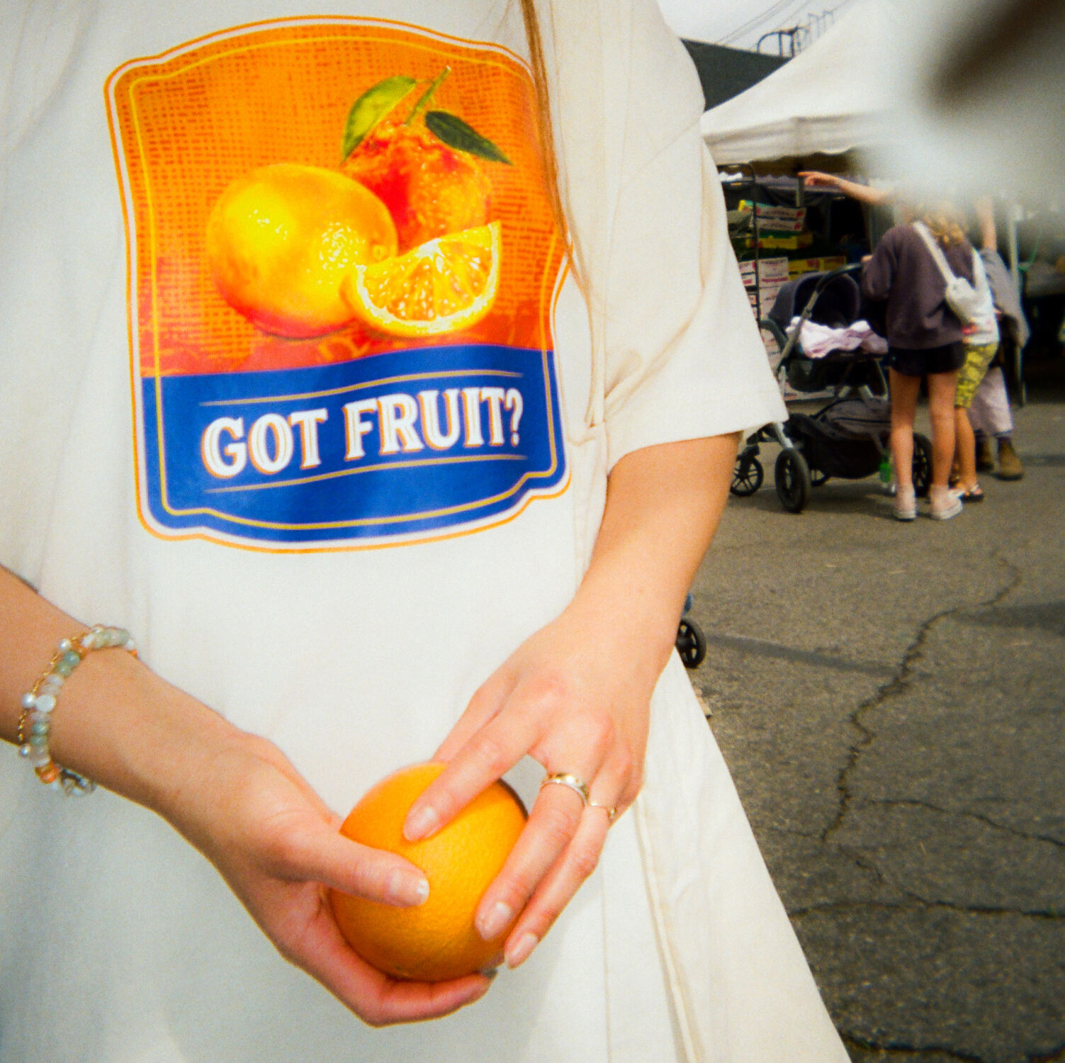 A person holding an orange in front of the Got Fruit? tee